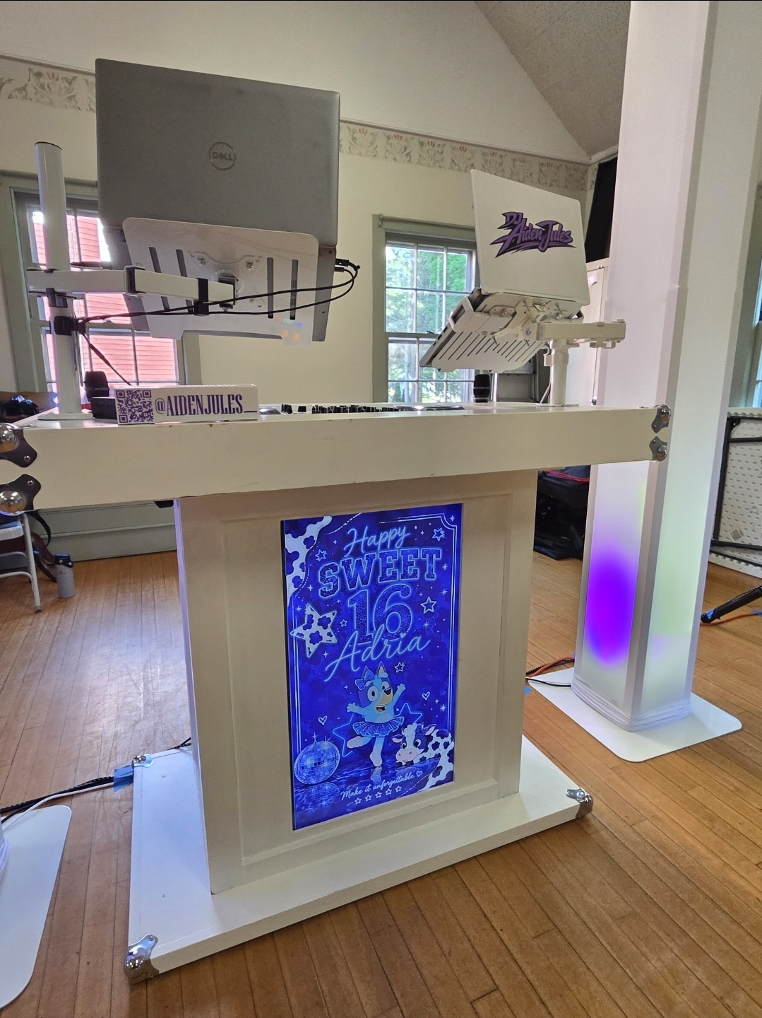 Custom DJ Aiden Jules booth with Happy Sweet 16 Adria display panel and glowing purple accent light