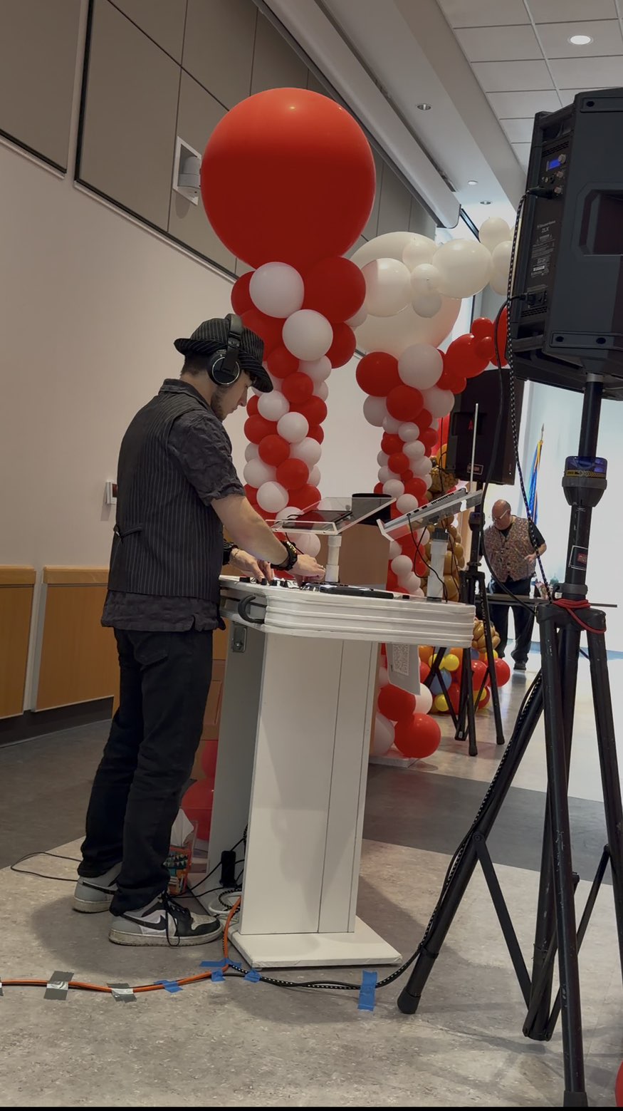 DJ Aiden Jules performing at a private party with a red and white balloon arch backdrop
