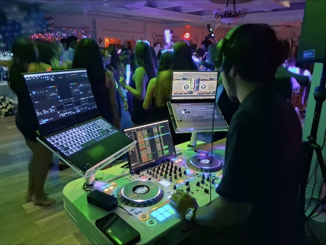 DJ Aiden Jules mixing on dual laptops with a crowded Quinceañera dance floor