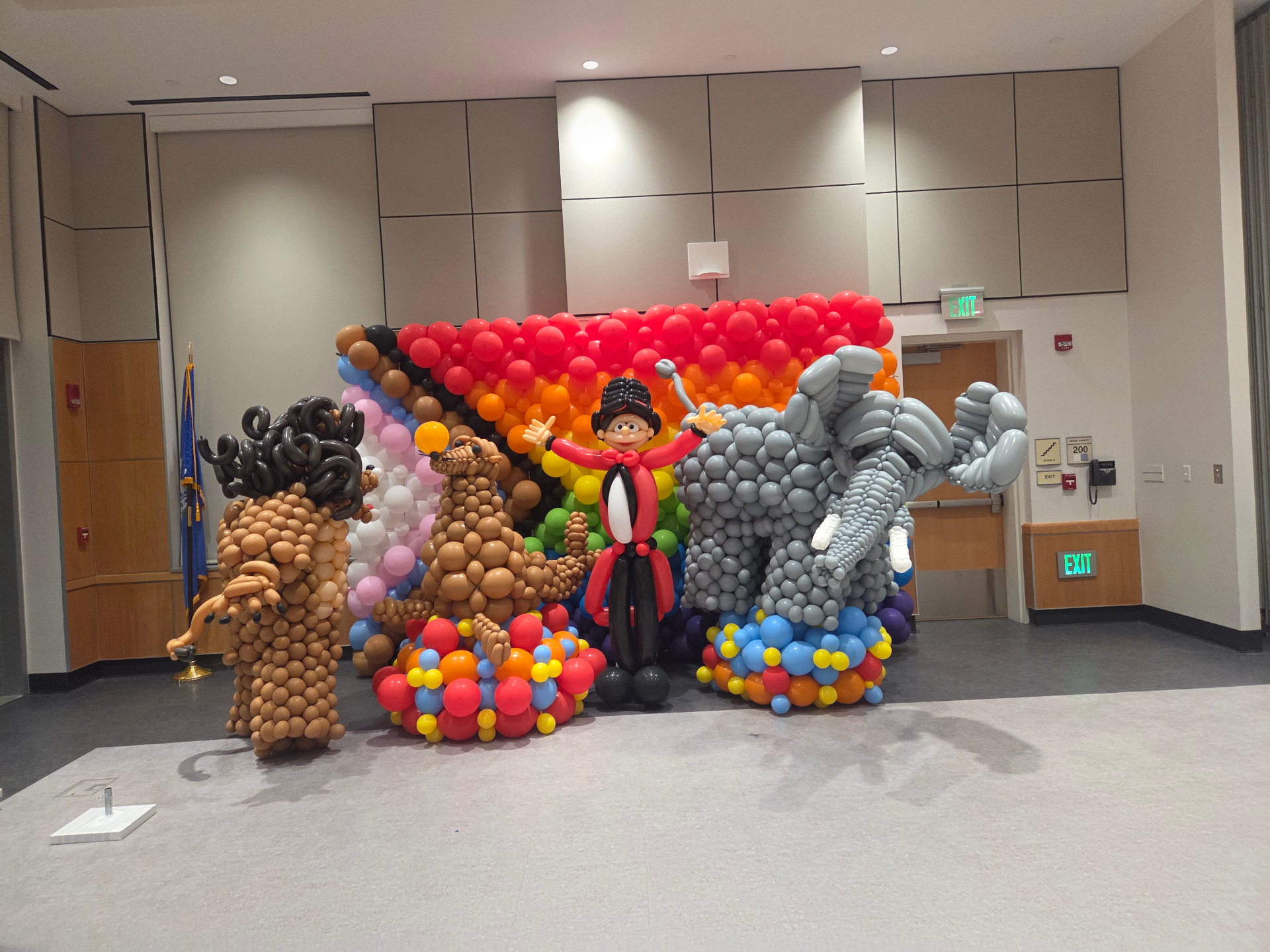 Colorful balloon installation at a college event featuring cartoon-style balloon sculptures and a rainbow backdrop