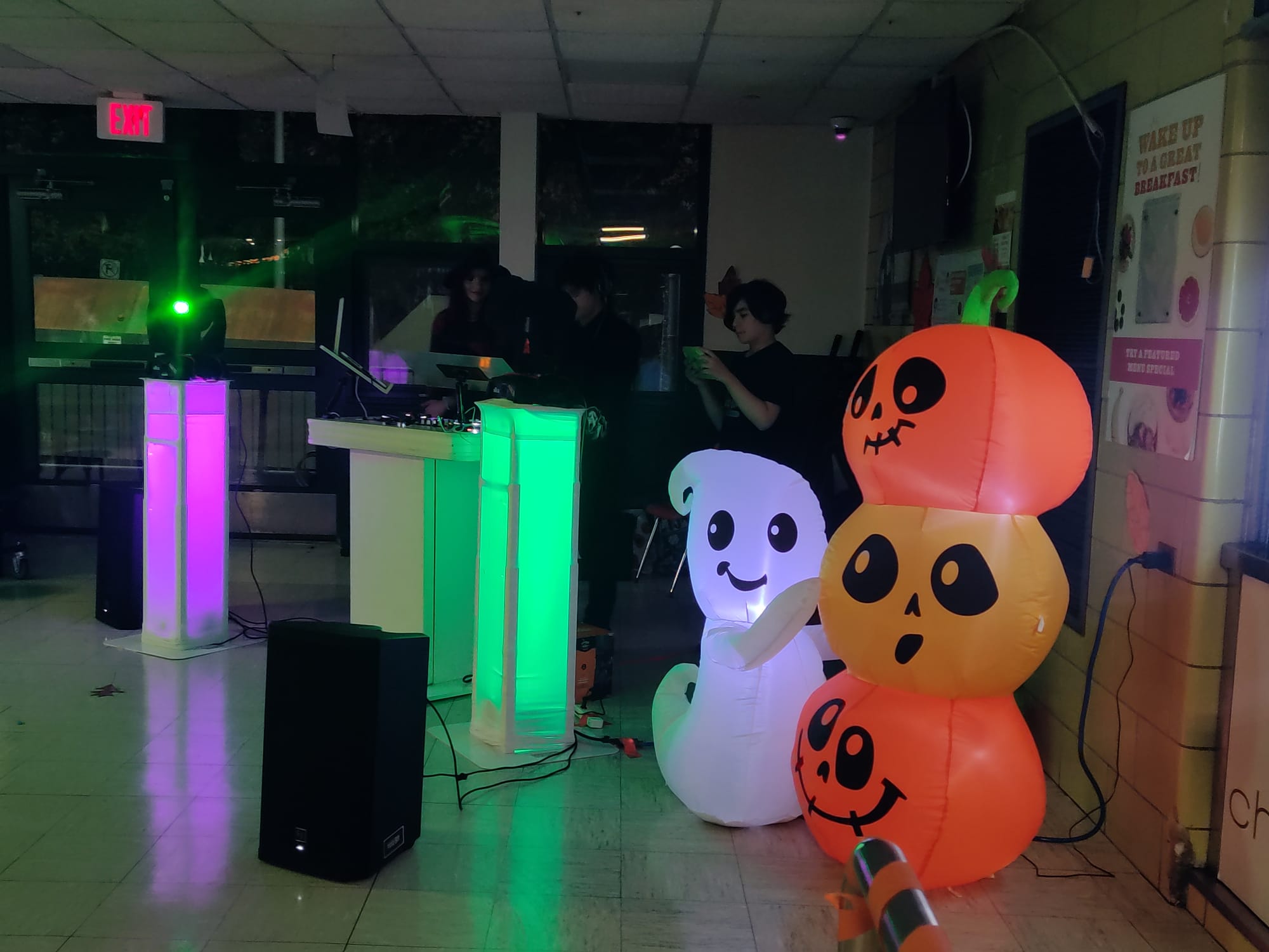 School event DJ setup with glowing pillar lights and seasonal decor at an evening student event